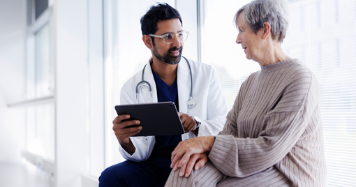 Doctor going over data on a tablet with an older patient. 