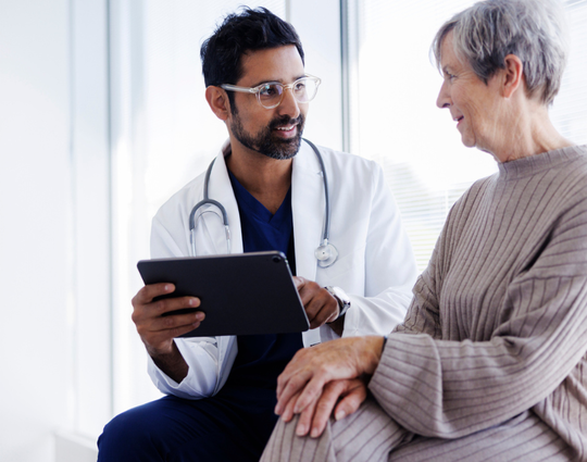 Doctor going over data on a tablet with an older patient. 