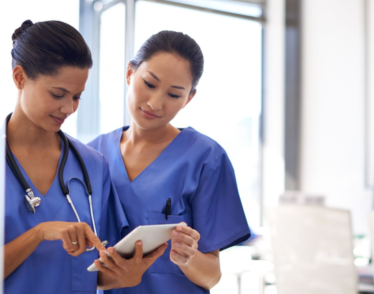 Shot of two female nurses using a tablet to review medical records