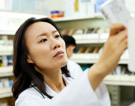 Close-up of female pharmacist arranging drugs on rack