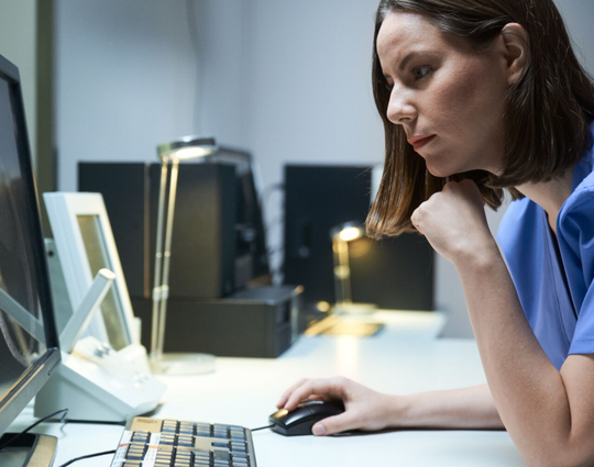 Female lab technician looking at scan after MRI in hospital laboratory.