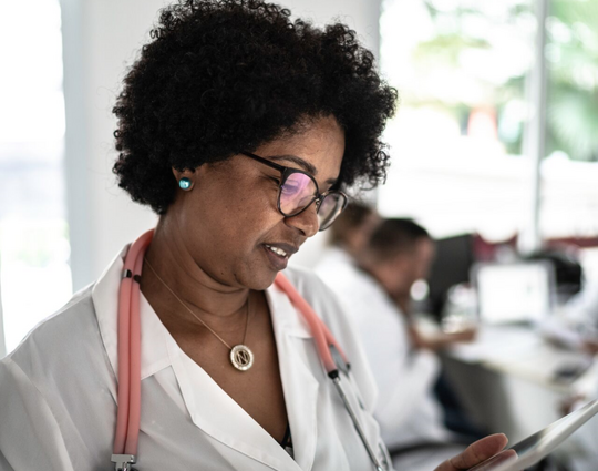 Portrait of mature female doctor using digital tablet with doctor's conference