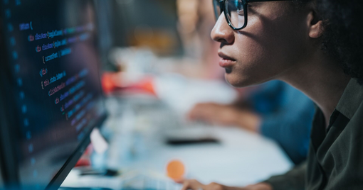 Focused female programmer coding new computer language while working on desktop PC in the office.