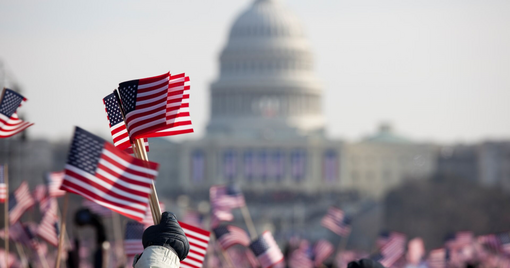 a crowd with american flags in front of a capitol building